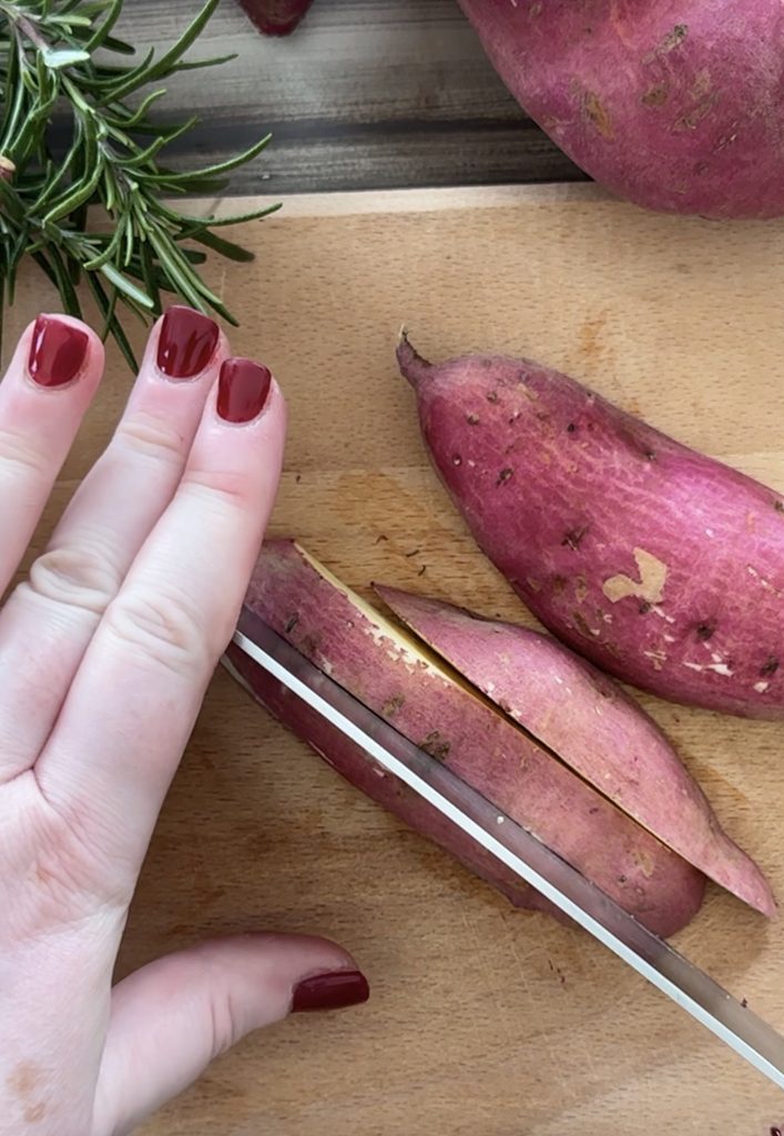 Mani di Monica che tagliano una batata rossa a spicchi con un coltello.