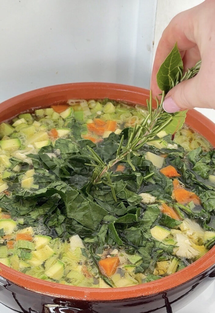 mano che aggiunge erbe al minestrone di fine settembre
